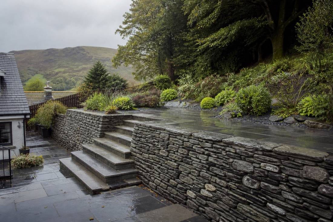Two slate terraces linked by wide stone steps behind a Cumbrian house